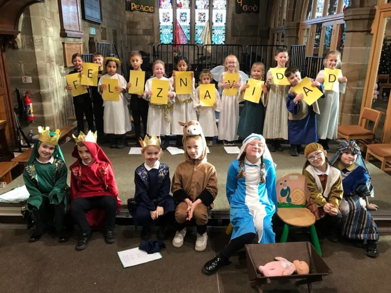 Children holding out cards that spell Feliz Navidad